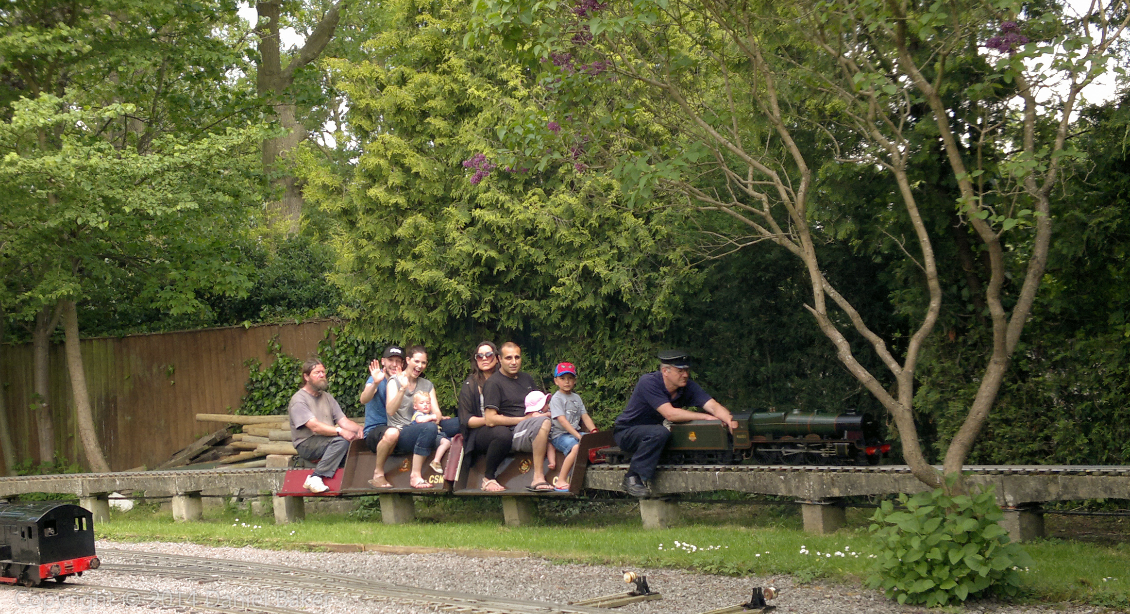 picture of a model steam locomotive with a carriage with people sitting on