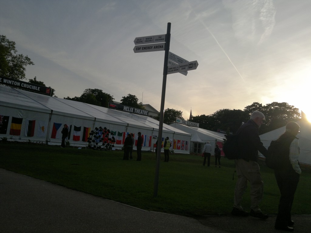 Picture of a sign with tents behind and sun low in the sky