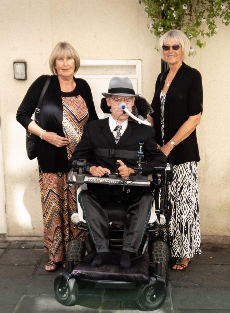 Daniel sitting in his wheelchair with his Aunt and Mother standing either side dressed up ready to watch The Price