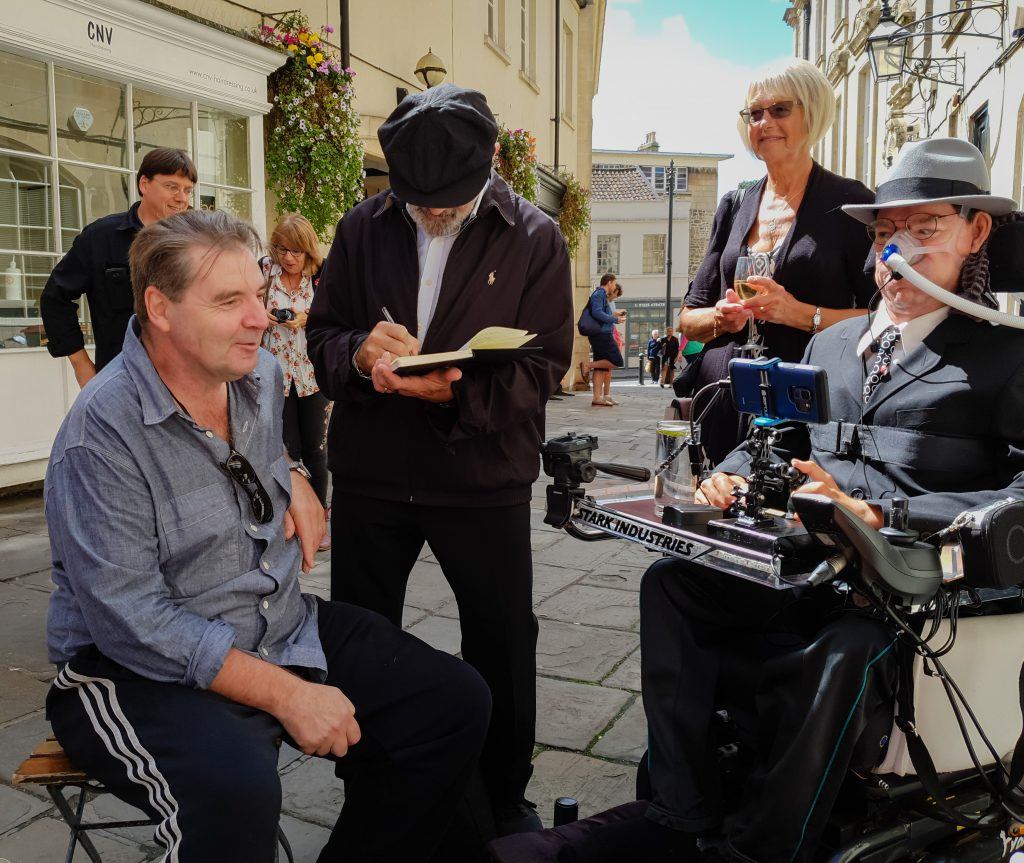 Brenden Coyle sitting and chatting with Daniel with David Suchet in the background signing an autograph with Daniel's Aunt beside him