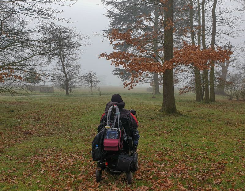 Daniel Baker in his wheelchair facing into the fog in woodland 