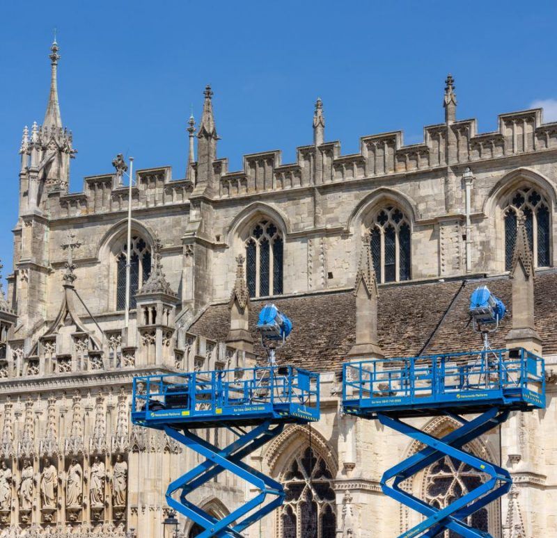 Blue metal hydraulic platforms supporting spotlights in front of Gloucester Cathedral