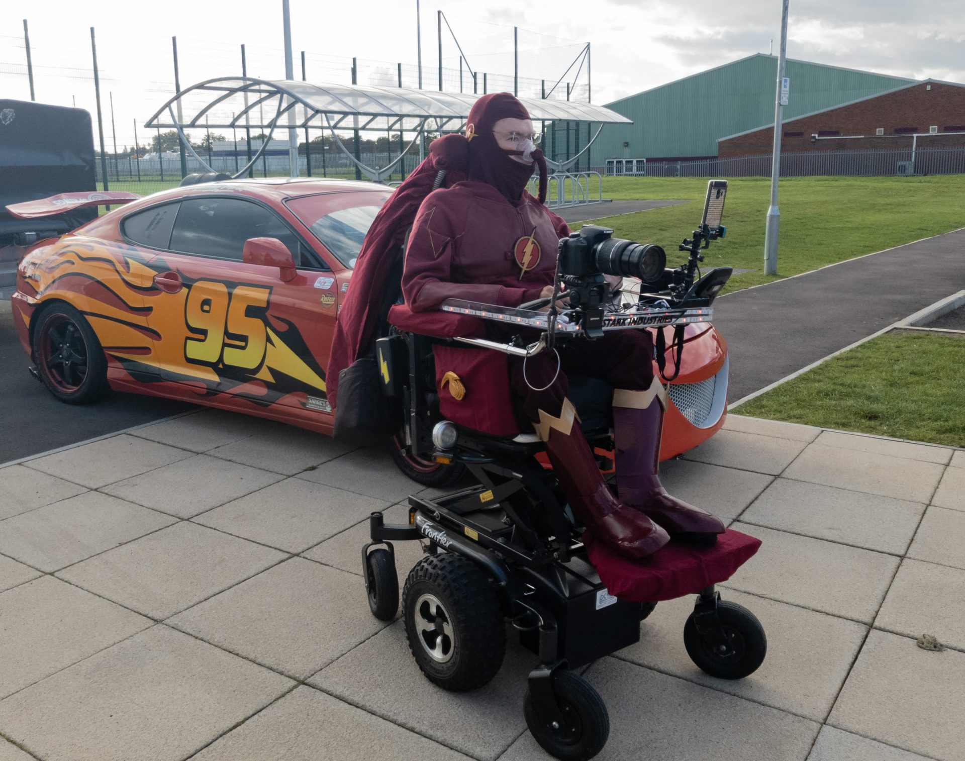 Geekmania Gloucester Daniel Baker dressed as The Flash in front of the car from Cars