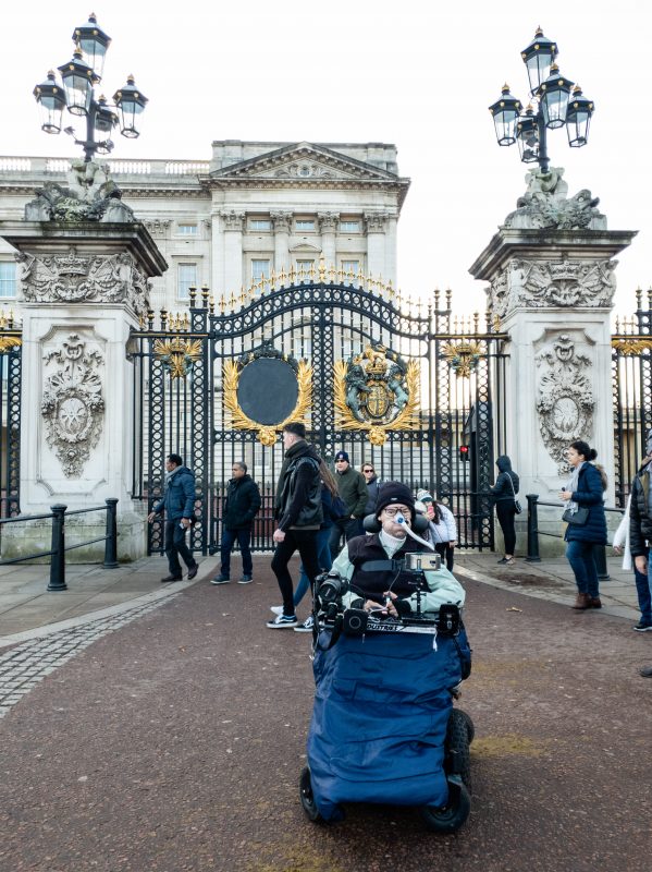 Daniel Baker sitting outside the gates of Buckingham Palace on his December London Trip