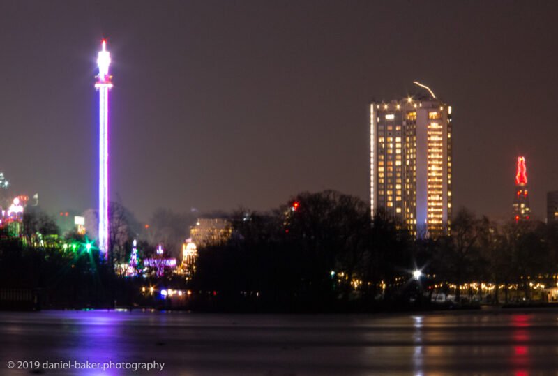 Winter Wonderland at night with London cityscape reflecting on the river in Hyde Park