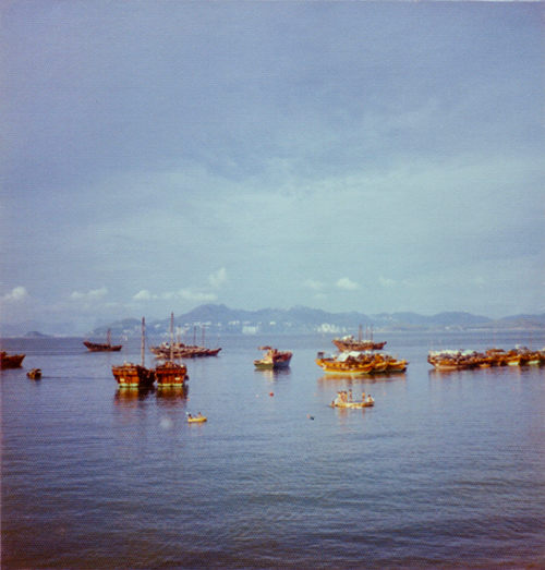 View of junks in the sea with mountains in the far distance. Hong Kong.