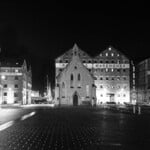 A black and white photo of a city at night, low angle viewing things from a different perspective