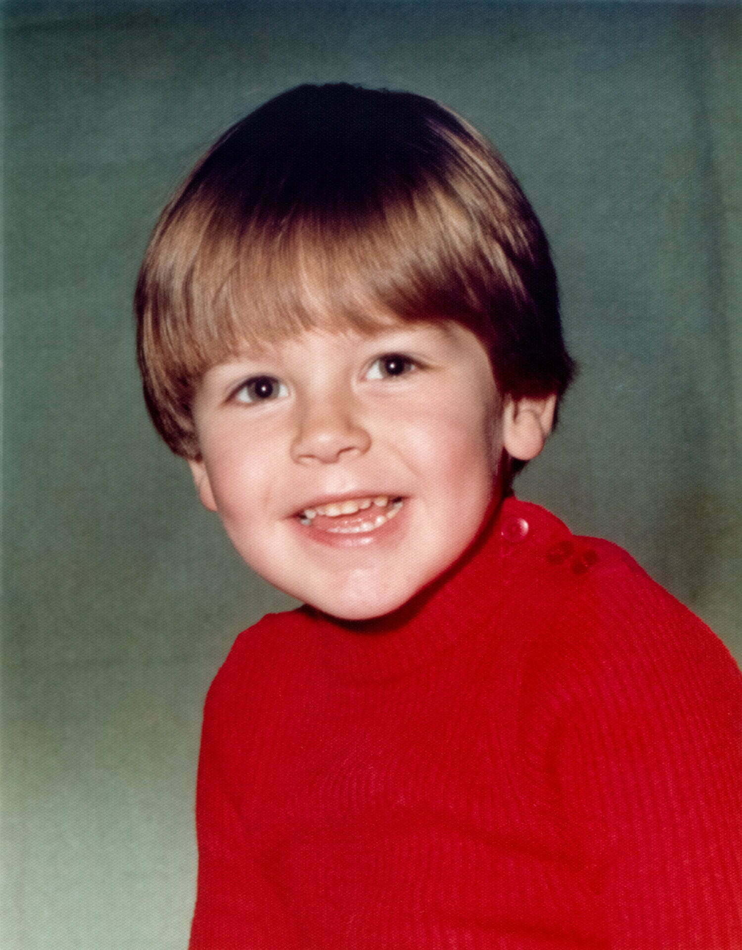 Portrait photo of a young Daniel Baker wearing a red jumper