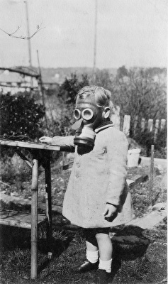 Black and white photo of a young child wearing a gas mask