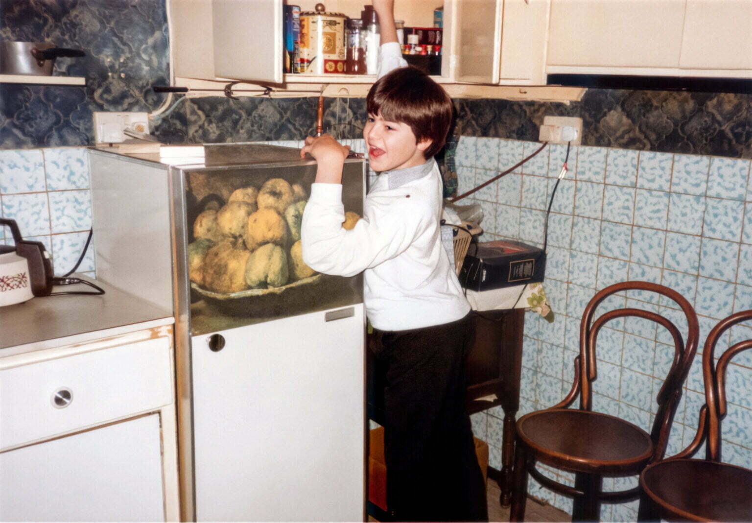 A young Daniel Baker in front of a fridge which has a picture of fruit on it