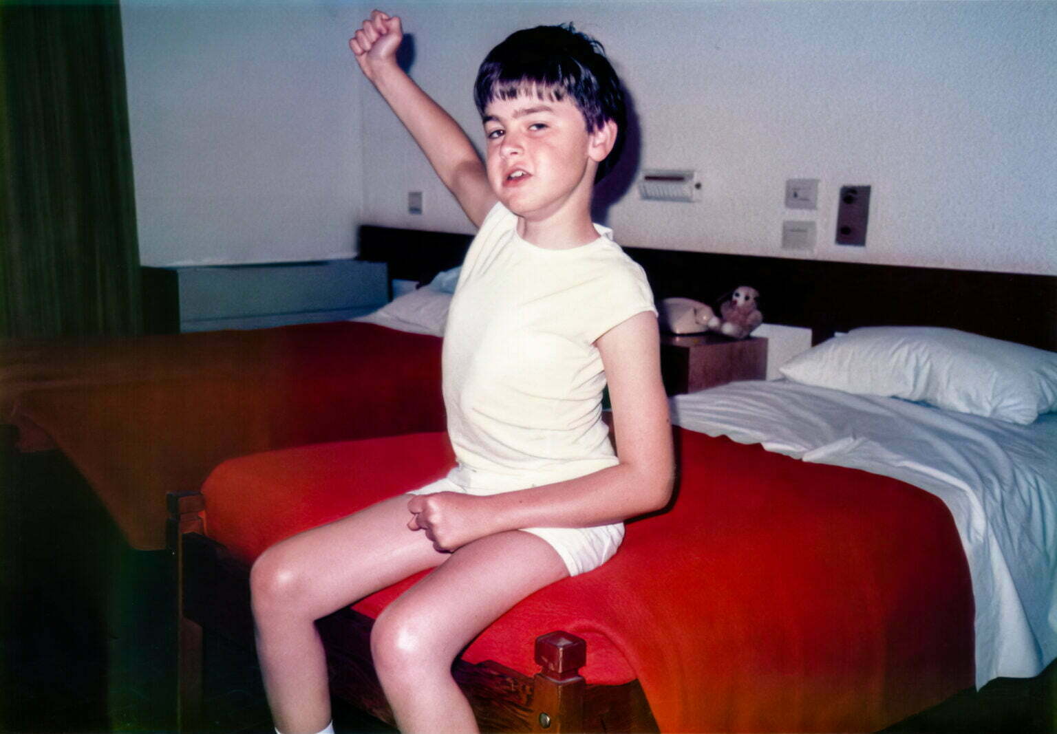 a young boy sitting on top of a red bed.