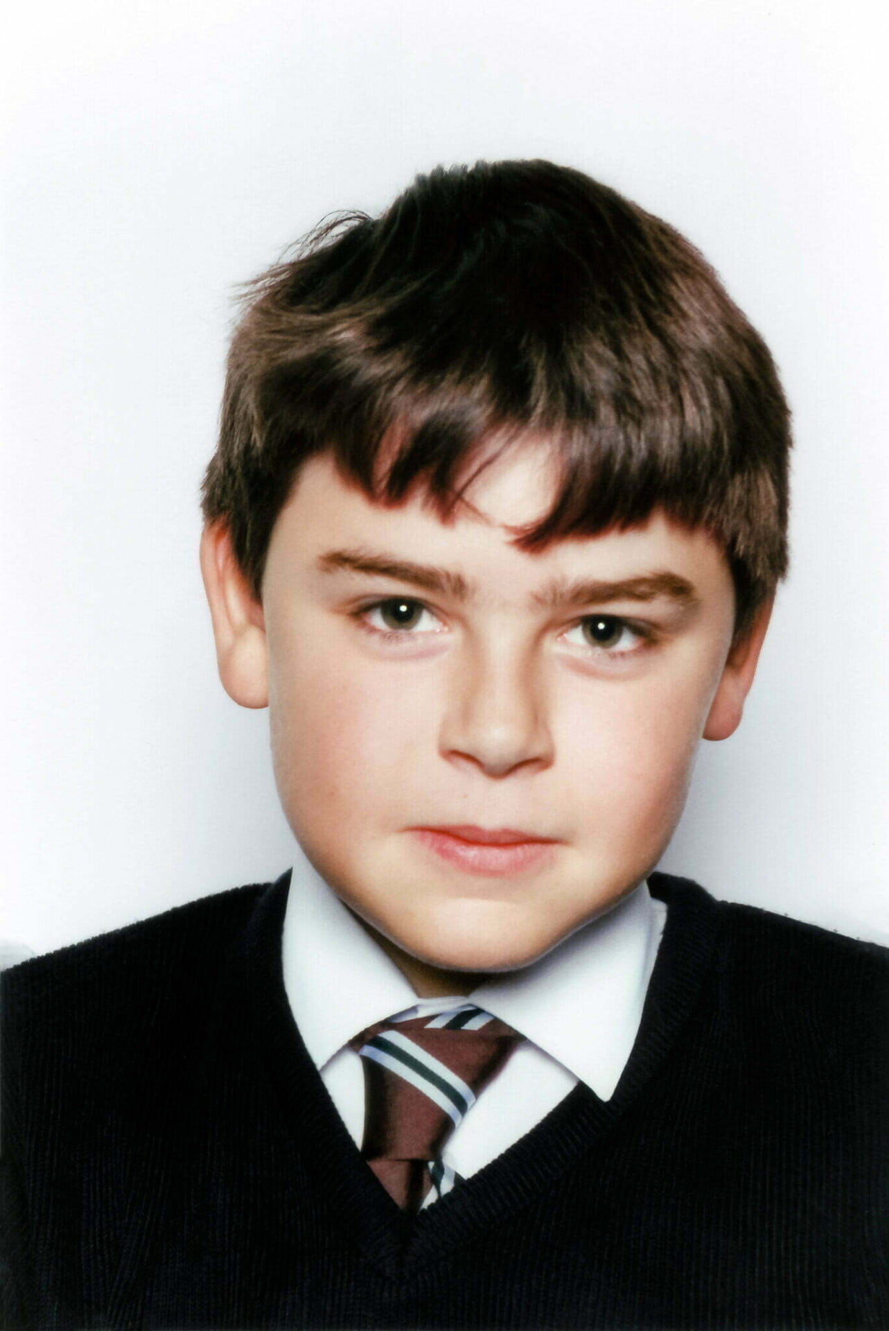 school photo of Daniel Baker wearing a sweater and tie.