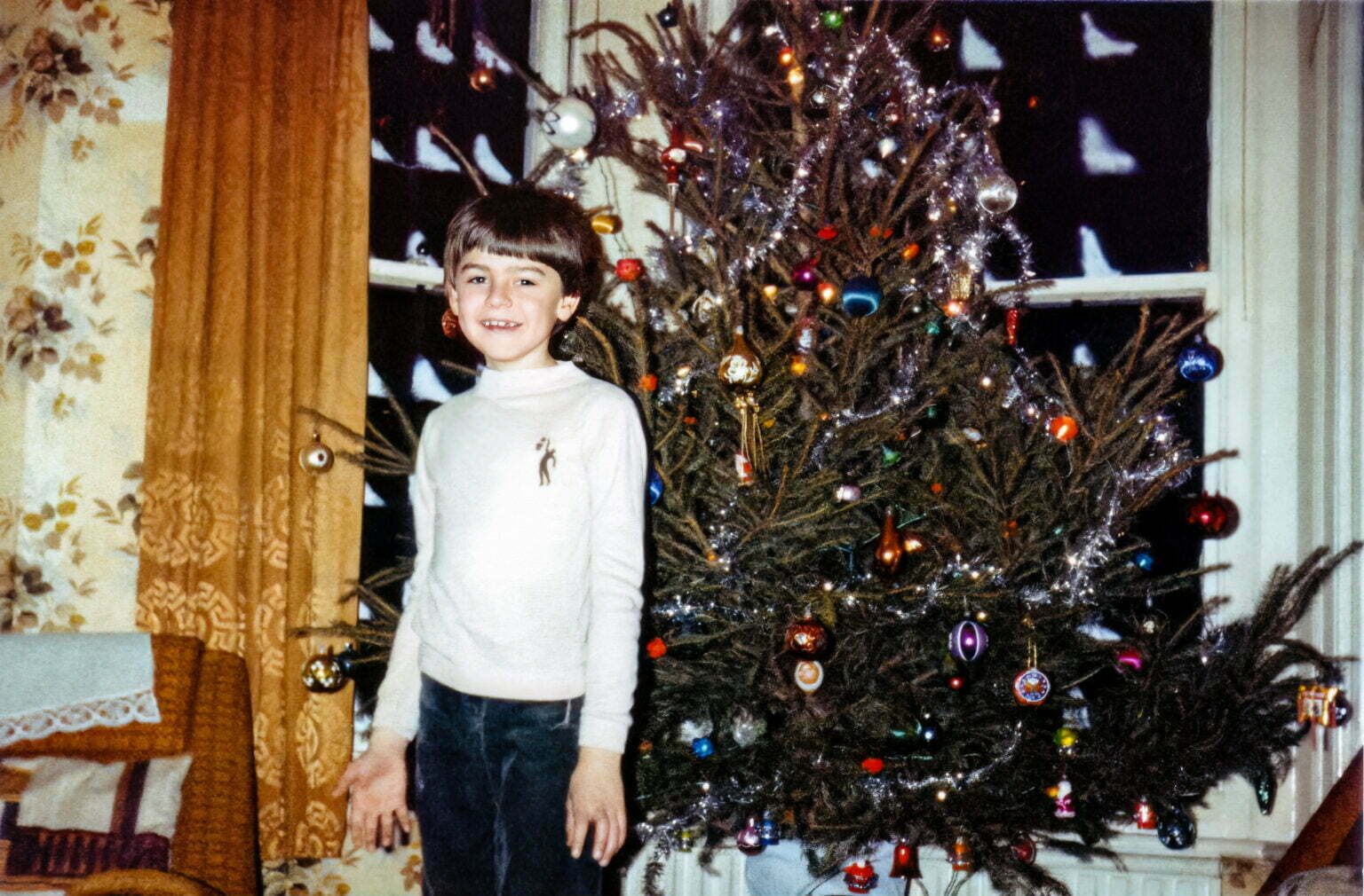 A young Daniel standing next to a Christmas tree