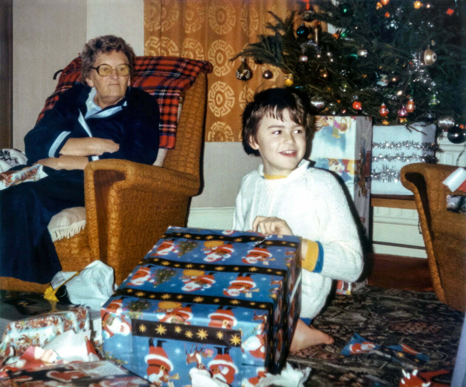 an old photo of an older woman and a child opening Christmas presents.