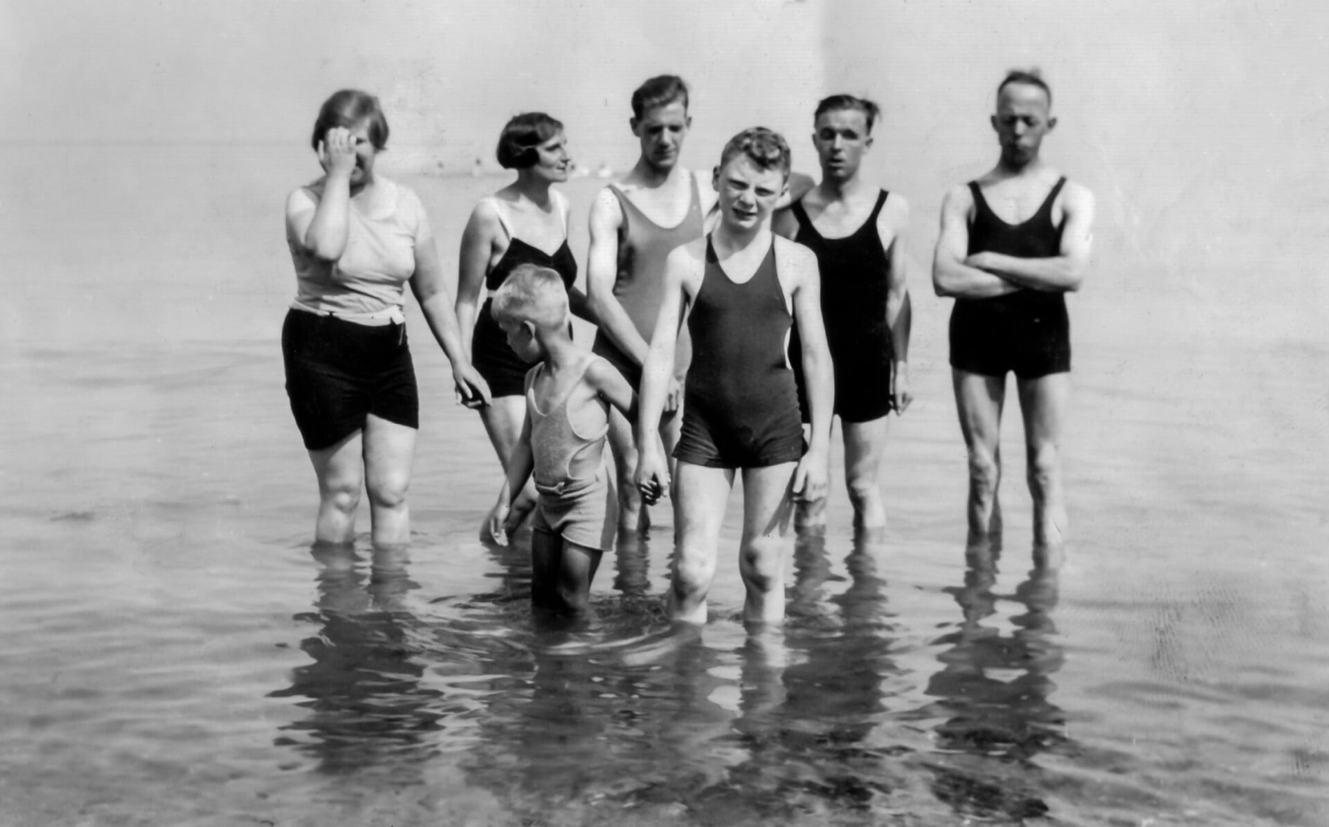 Black and white photo of a family padding in the sea
