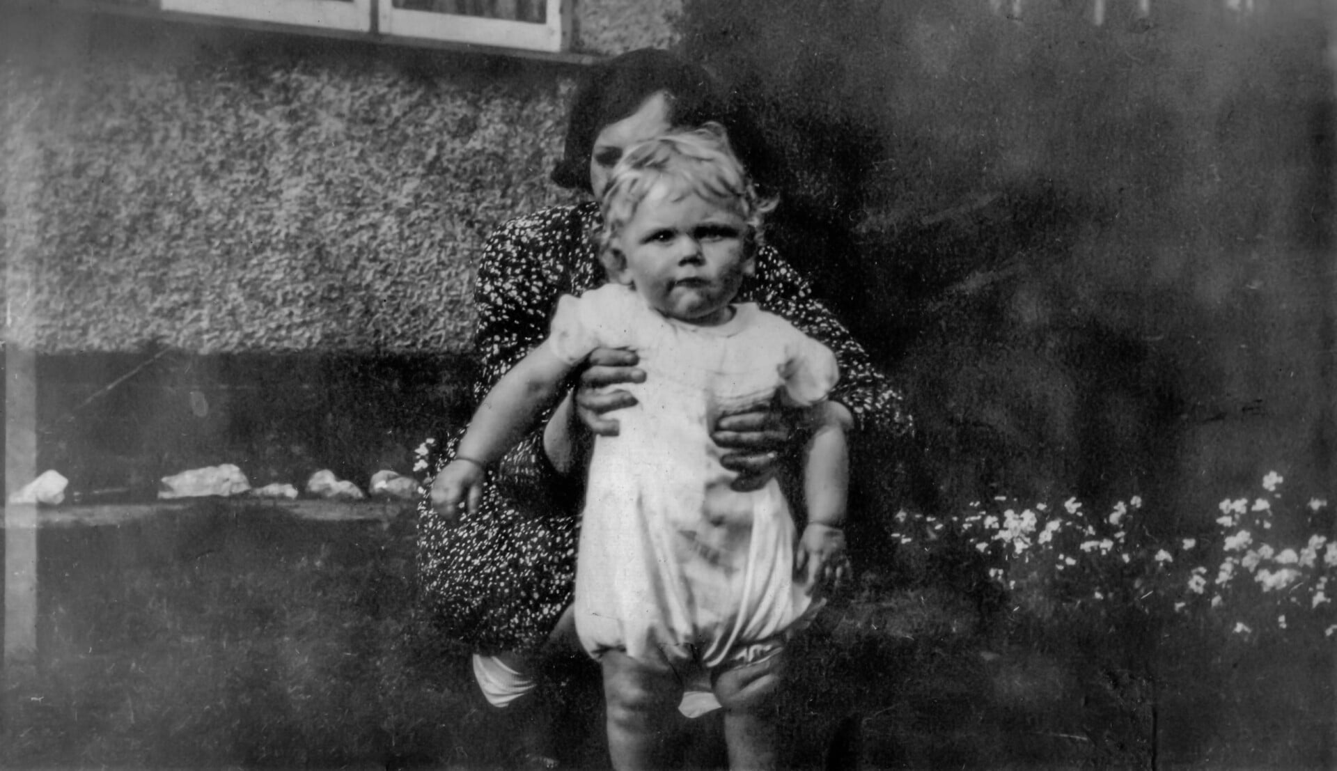 Black and white photo of a woman holding a baby in a garden