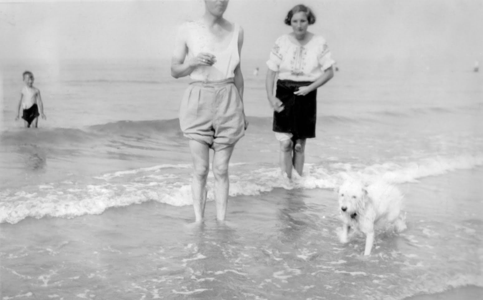 Black and white photo of a man, woman and a og in the sea